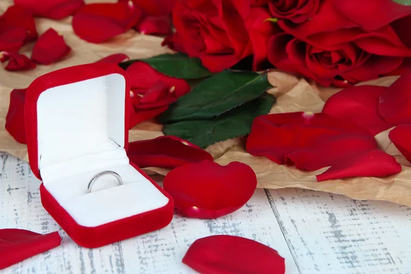 Anillo rodeado de rosas y pétalos en la mesa de madera de cerca —  Fotos de Stock