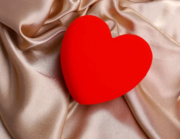 Декоративное красное сердце, на фоне цветной ткани — стоковое фото