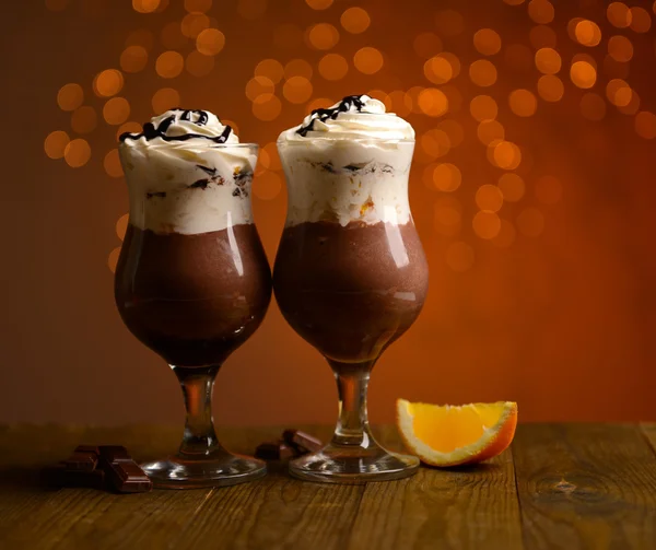 Lekker dessert met oranje, chocolade en crème saus, op houten tafel, op lichten achtergrond — Stockfoto