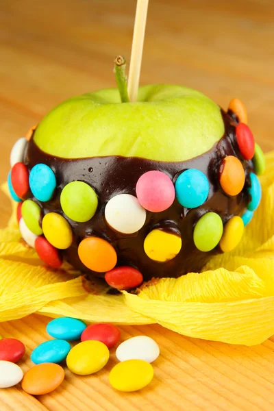 Candied apple on stick on wooden table — Stock Photo, Image