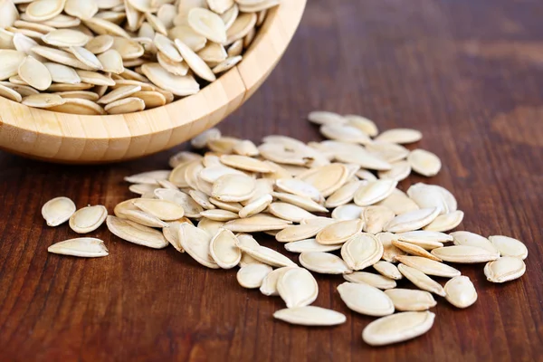 Pumpkin seeds in bowl on wooden background — Stock Photo, Image