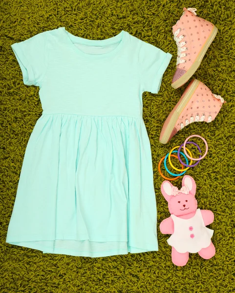 Mooie jurk en gumshoes voor meisje op groene tapijt — Stockfoto