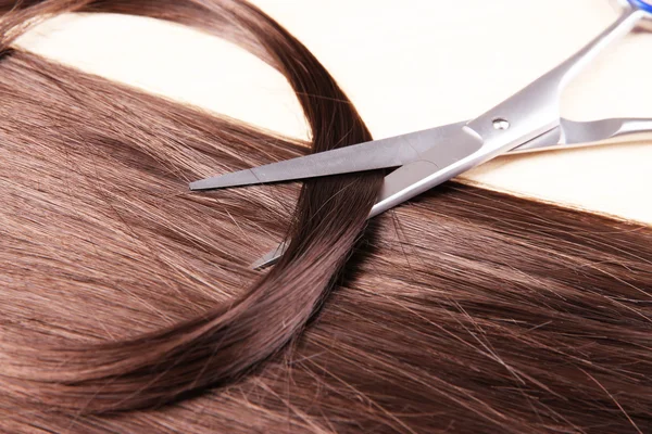 Long brown hair and scissors on wooden background — Stock Photo, Image