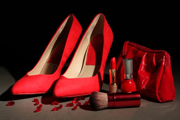 Belle scarpe rosse femminili e cosmetici, su sfondo nero — Foto Stock