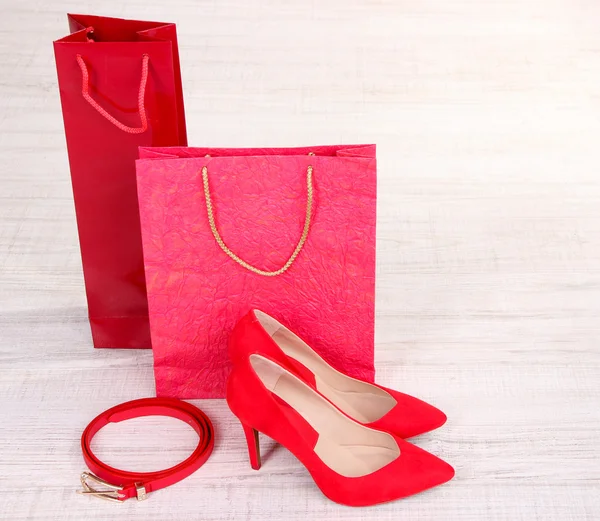 Hermosos zapatos femeninos rojos, cinturones y bolsas de compras — Foto de Stock