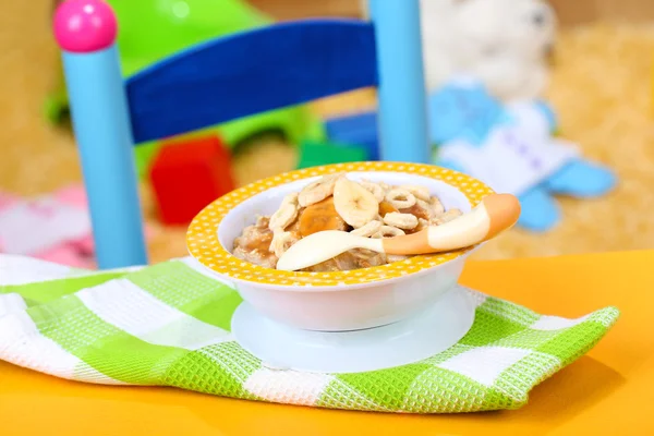 Bowl of porridge for baby and toys on table, on toys background — Stock Photo, Image