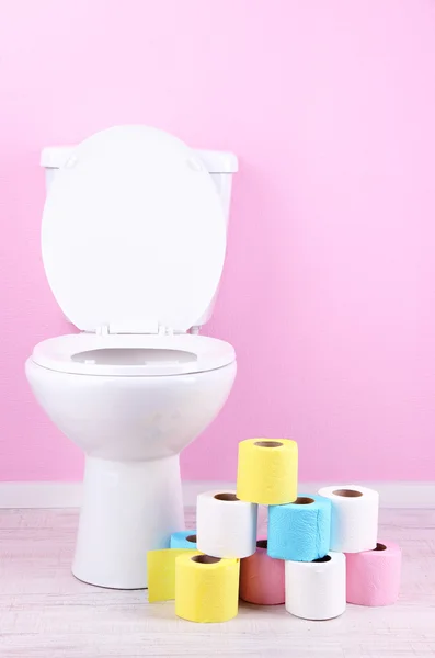 White toilet bowl and colorful rolls of toilet paper, in bathroom — Stock Photo, Image