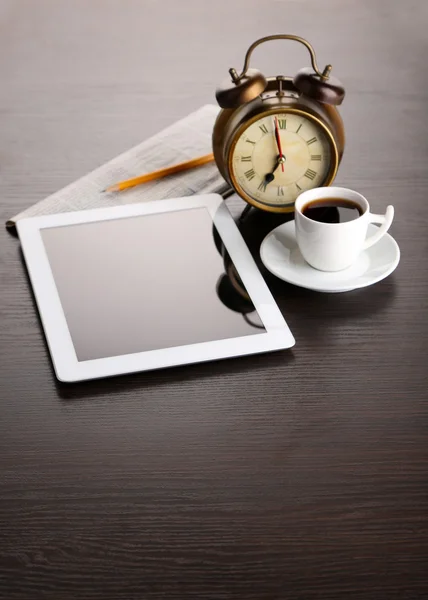 Tablett, tidning, kopp kaffe och väckarklocka på träbord — Stockfoto