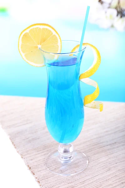 Glass of cocktail on table on light blue background — Stock Photo, Image