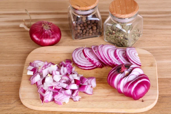 Geschnittene Zwiebel auf Schneidebrett auf Holzgrund — Stockfoto