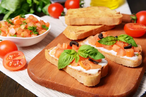 Deliciosa bruschetta con tomates en la tabla de cortar de cerca —  Fotos de Stock