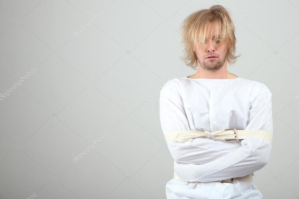 Mentally ill man in strait-jacket on gray background