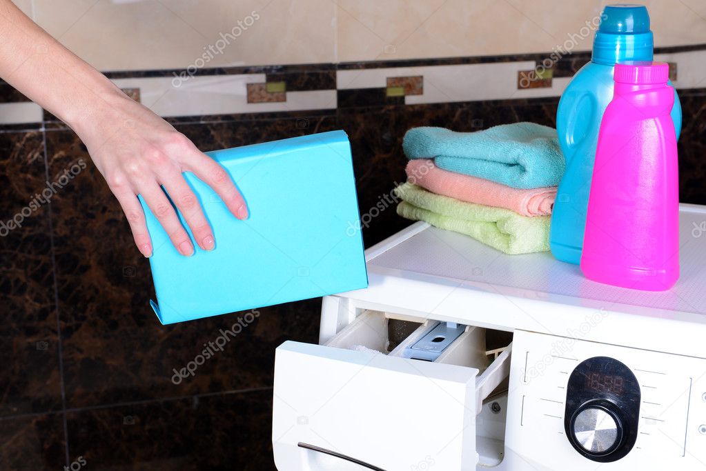 Female hands poured powder in washing machine close-up