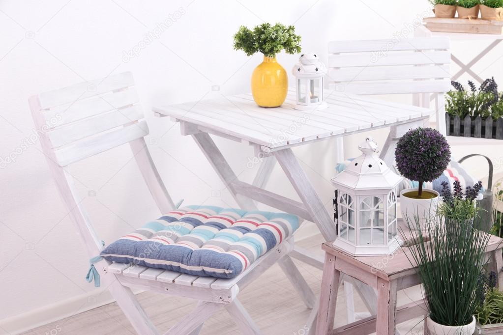 Garden chairs and table with flowers on wooden stands on white background