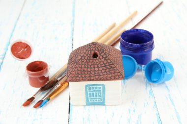 el yapımı ahşap masanın üzerine seramik ev ve renk boyalar