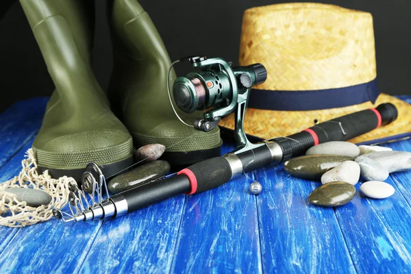 Рыболовный прут, резиновые сапоги и шляпа на деревянном столе крупным планом — стоковое фото