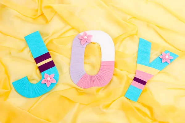 Word Joy creato con vivacemente colorato cantiere di maglieria su sfondo tessuto — Foto Stock