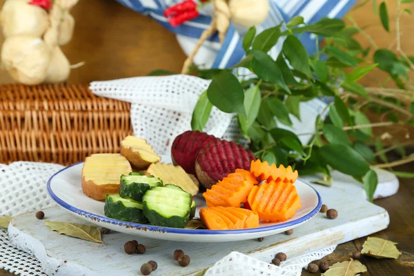 Hermosas verduras en rodajas, en plato, sobre fondo de madera — Foto de Stock