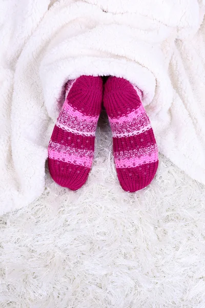 Pernas femininas em meias coloridas no fundo do tapete branco — Fotografia de Stock
