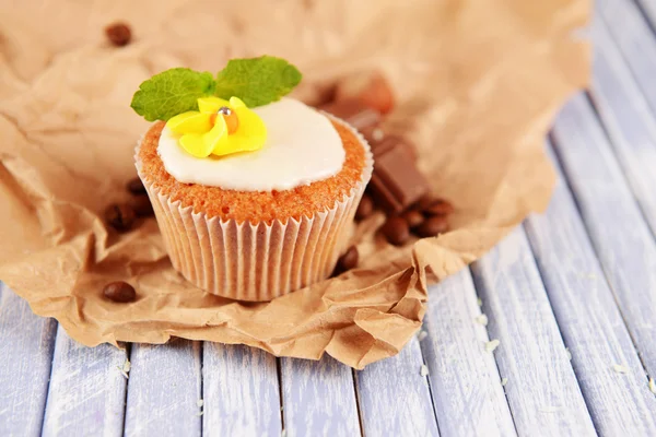 Tasty cupcake with butter cream, on color wooden table, on wooden background — Stock Photo, Image