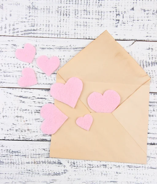 Beautiful old envelope with decorative hearts on wooden background — Stock Photo, Image