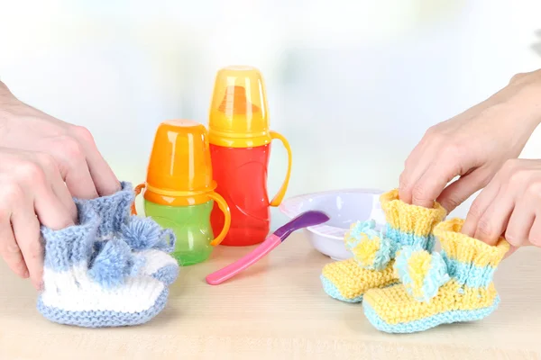 Hands with crocheted booties for baby, on light background — Stock Photo, Image