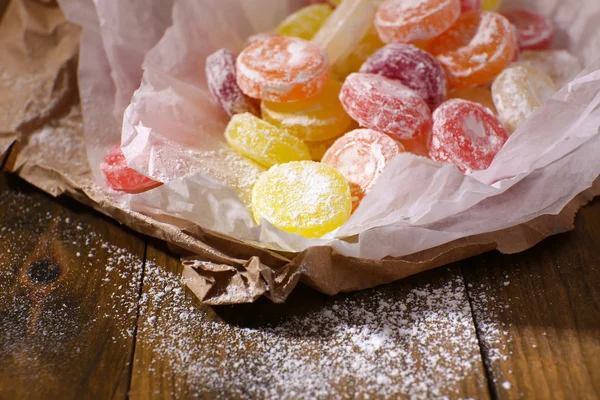 Sweet multicolor candies on paper, on wooden background — Stock Photo, Image