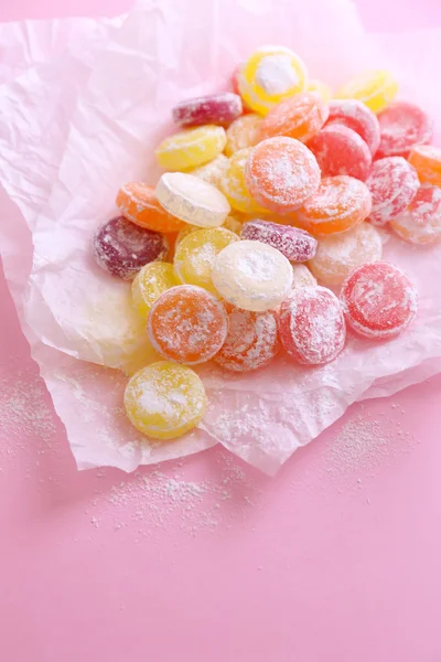 Sweet multicolor candies on paper, on color background — Stock Photo, Image