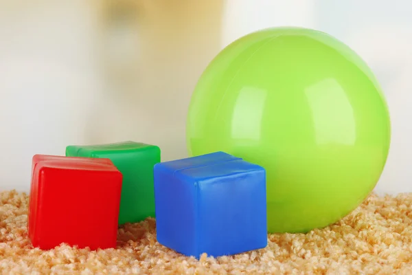 Ljusa boll och färgglada kuber på mattan på ljus bakgrund — Stockfoto