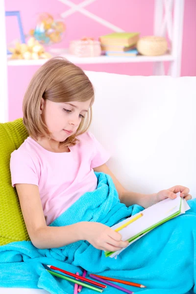 Küçük kız odasında kanepede oturan çizer — Stok fotoğraf