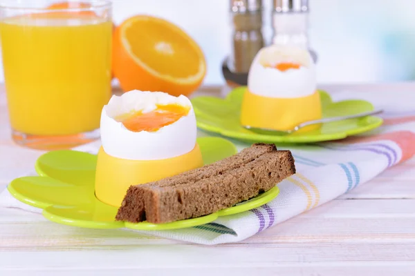 Boiled eggs in egg cups on table on light background — Stock Photo, Image