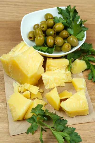 Parmesan, frische Kräuter und Oliven auf Holzgrund — Stockfoto