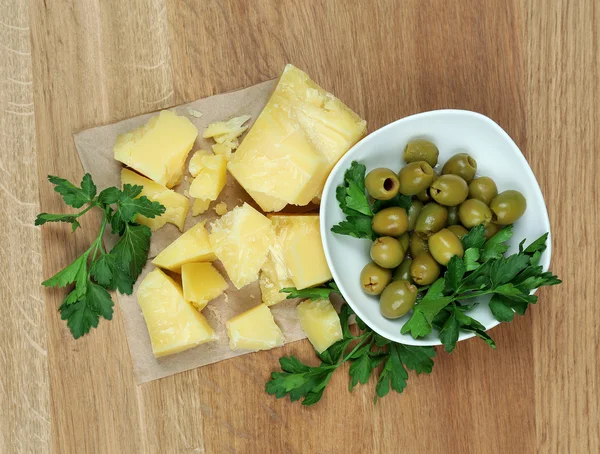 Parmesan cheese, fresh herbs and olives on wooden background — Stock Photo, Image