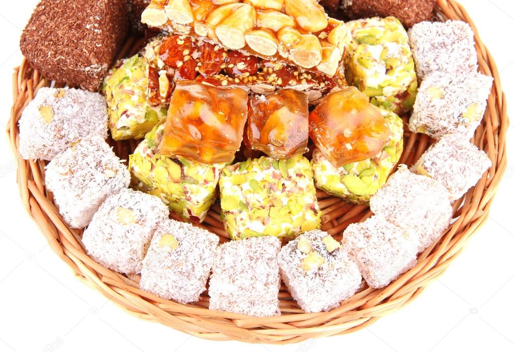 Tasty oriental sweets on wicker tray, isolated on white