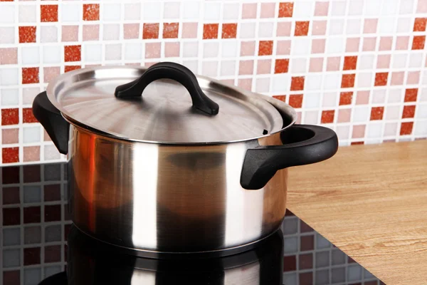 Maceta en la estufa en la cocina en la mesa en el fondo de mosaico azulejos — Foto de Stock