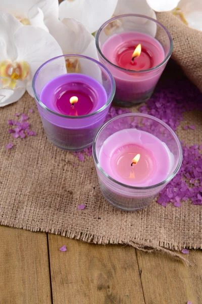 Composición con hermosas velas de colores, sal marina y flores de orquídea, sobre fondo de madera — Foto de Stock