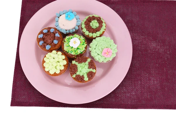 Smakelijke cupcakes met boter room, op plaat, op kleur servet. geïsoleerd op wit — Stockfoto