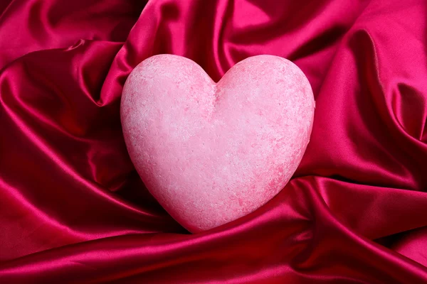 Dekoratives rotes Herz, auf farbigem Stoffhintergrund — Stockfoto