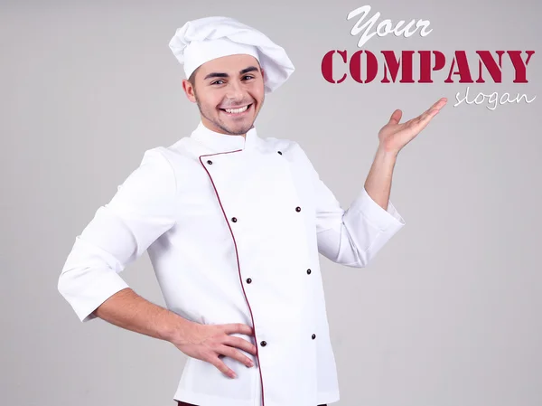 Chef profesional en uniforme blanco y sombrero, sobre fondo gris — Foto de Stock