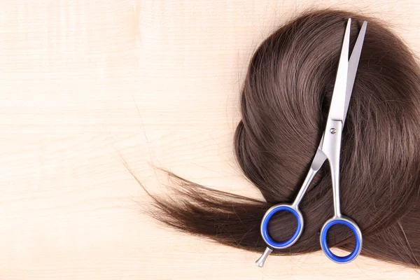 Lange braune Haare und Schere auf Holzgrund — Stockfoto