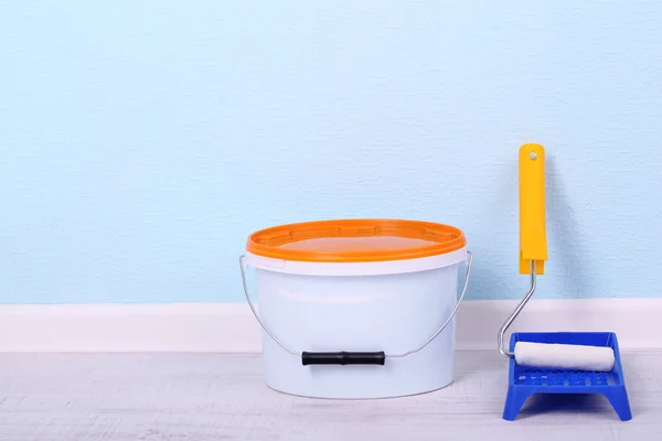 Pintura y rollo en el suelo en la habitación sobre fondo de pared — Foto de Stock