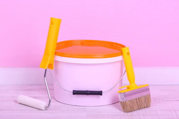 Pintura, rollo y pincel en el suelo en la habitación en el fondo de la pared — Foto de Stock