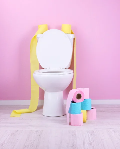 Weiße Toilettenschüssel und bunte Rollen Toilettenpapier im Badezimmer — Stockfoto