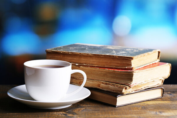 Чашка горячего чая с книгами на столе на ярком фоне
