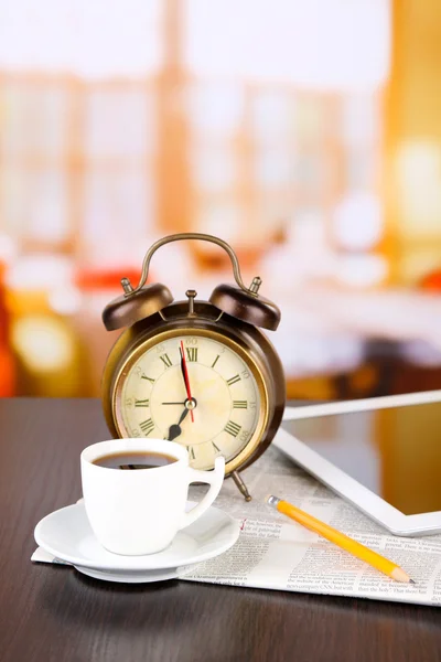 タブレット、新聞、コーヒーのカップと木製のテーブルの上の目覚まし時計 — ストック写真