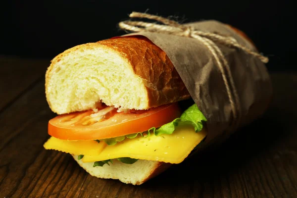 Fräsch och välsmakande smörgås på träbord på svart bakgrund — Stockfoto