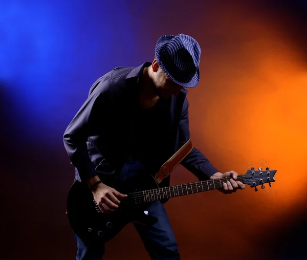 Young musician playing guitar on dark color background Royalty Free Stock Images