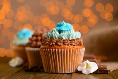 Işıklar arka plan üzerinde ahşap masa üzerine tereyağı krema ile lezzetli kekler