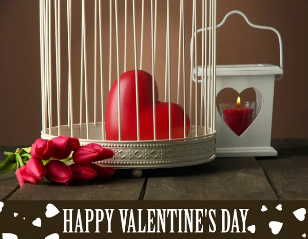 Corazón en jaula decorativa sobre mesa de madera, sobre fondo marrón — Foto de Stock