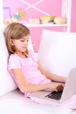 oturma odasındaki kanepe üstünde laptop ile küçük kız